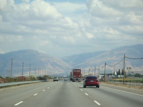 1990 Ford Taurus - A view from a vehicle traveling on a highway, with other cars and a truck ahead, under a cloudy sky.