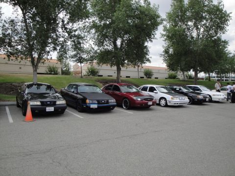 1990 Ford Taurus - A row of sedans, including a 1990 Ford Taurus, are parked in an outdoor lot.