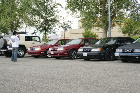 1990 Ford Taurus - A line of Ford Taurus sedans, likely from the late 1980s, are parked together in an outdoor lot.