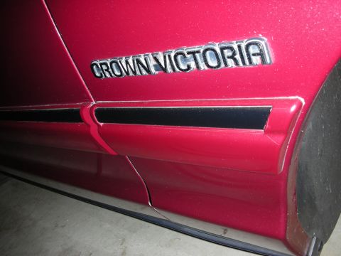 1992 Ford Crown Victoria - The side panel of a red vehicle displays the 'CROWN VICTORIA' badging.