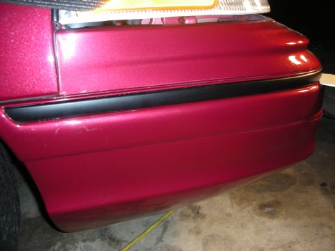 1992 Ford Crown Victoria - Close-up of the rear bumper and taillight assembly on a red 1992 Ford Crown Victoria.