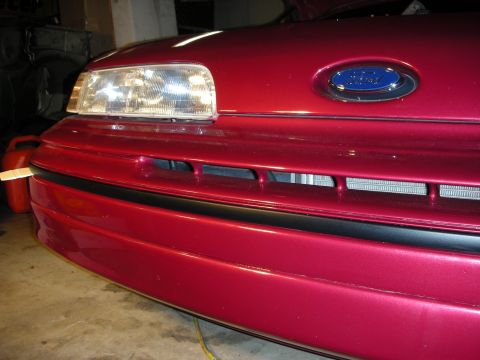 1992 Ford Crown Victoria - Close-up of the front grille and headlights on a red 1992 Ford Crown Victoria.