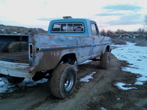 1971 Ford F-100 - Mud-splattered blue Ford F-Series truck parked on a dirt road with patches of snow.