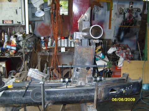 1989 Ford Bronco - A custom-fabricated bumper assembly is shown in a cluttered workshop setting, with various tools and supplies visible in the background.
