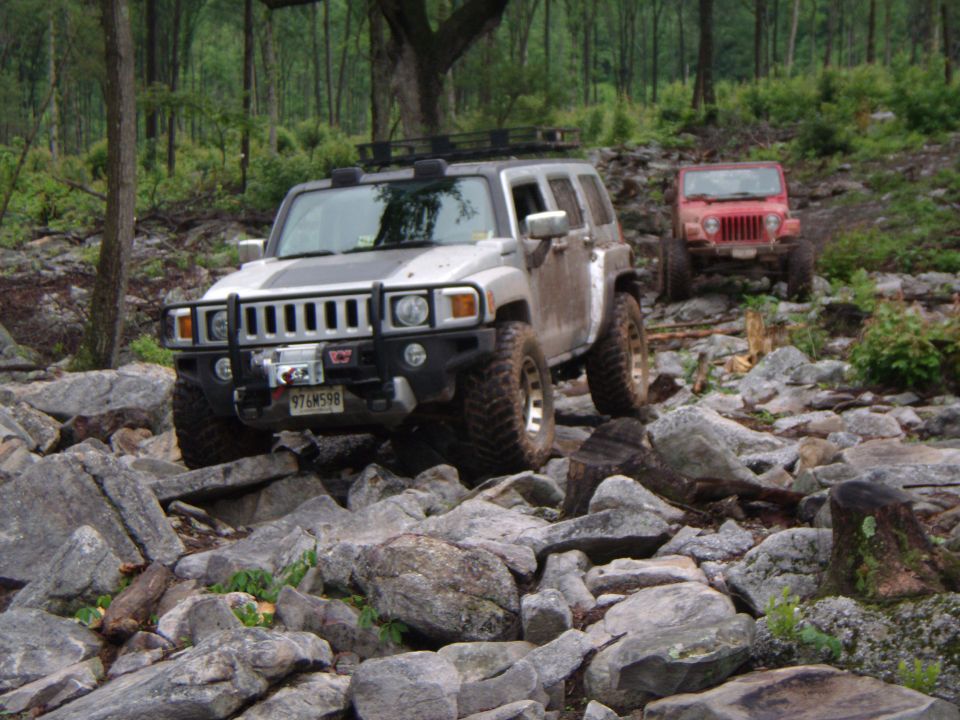 Silver Hummer H3 and red Jeep Wrangler driving on rocky terrain