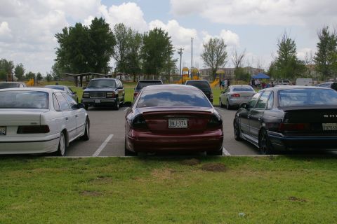 1990 Ford Taurus - A 1990 Ford Taurus is parked in a lot, showing its rear end with aftermarket taillights and a visible license plate.