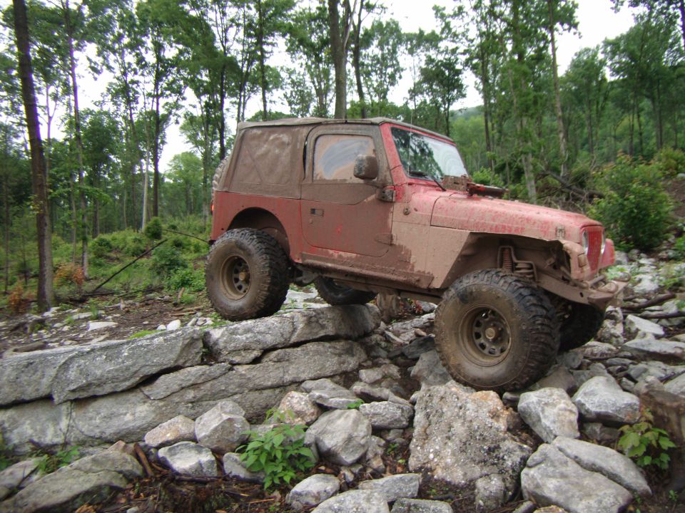 Red 2003 Jeep Wrangler navigating rocky terrain