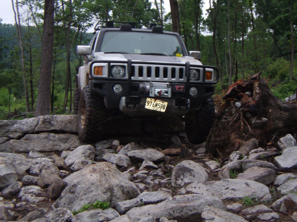 Silver Hummer H3 with winch and aftermarket bumper on rocky terrain