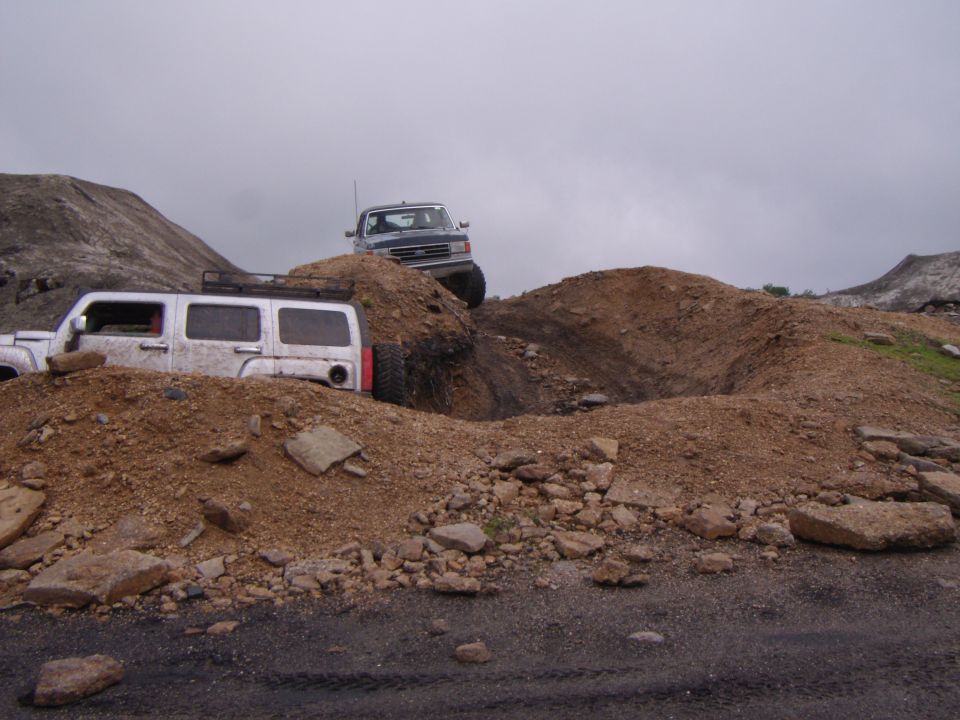 White SUV and blue pickup truck navigating dirt mounds off-road