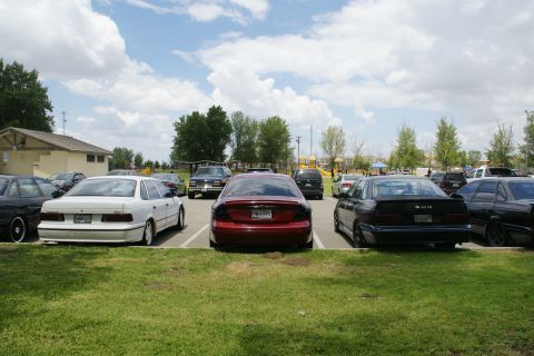1990 Ford Taurus - Several cars are parked in a lot on a cloudy day, with a white Ford Taurus in the foreground.