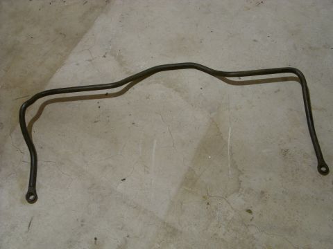 1988 Ford Bronco - A dark metal sway bar lies on a cracked concrete surface, casting a shadow.