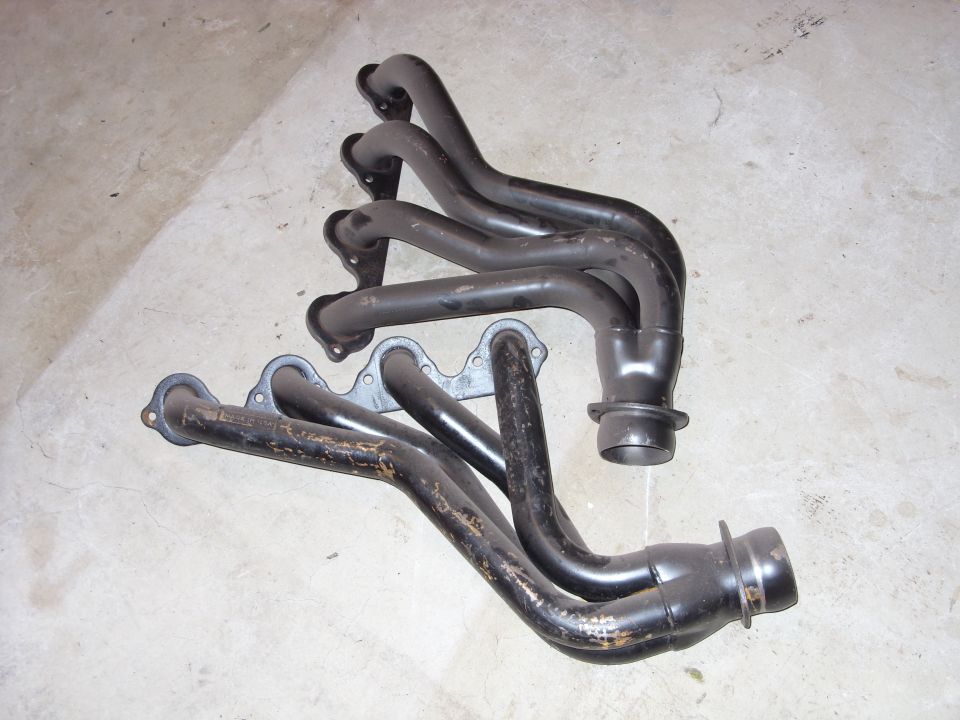 Two black exhaust headers on a concrete surface