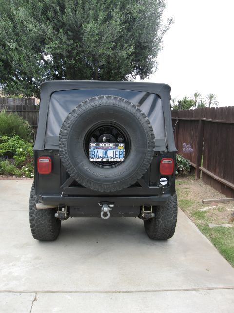 1986 Ford Bronco - Rear view of a black Jeep CJ with a spare tire mounted on the back and a custom bumper.
