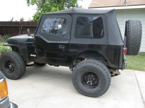1986 Ford Bronco - This black Jeep CJ7 features a soft top and a spare tire mounted on the rear.