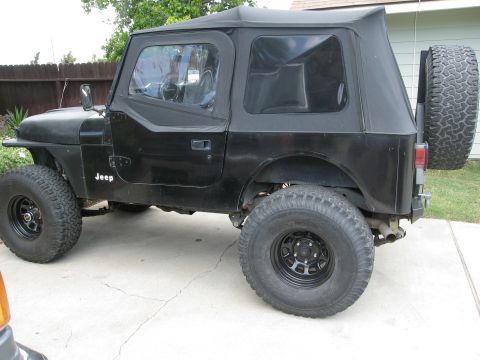 1986 Ford Bronco - This Jeep CJ7 is shown from the side, its soft top and spare tire mounted on the back.