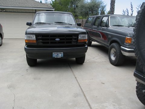 1986 Ford Bronco - A black Ford Bronco is parked in front of a garage, with another SUV behind it.