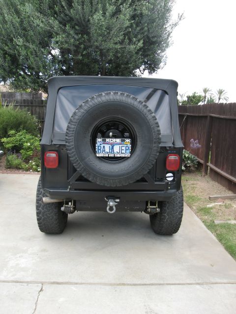 1986 Ford Bronco - This black Jeep CJ7 is shown from the rear, a spare tire mounted on the tailgate and a custom license plate.