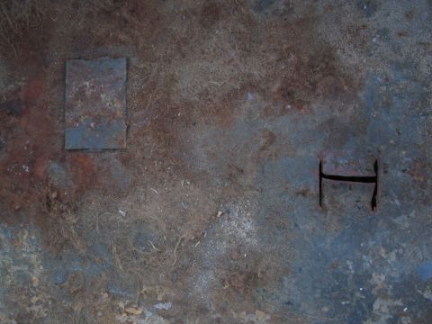 1986 Ford Bronco - Close-up of a heavily rusted floor panel, showing two distinct cutouts and signs of wear.