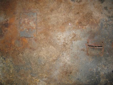 1986 Ford Bronco - This image shows a heavily rusted floor panel with a square patch and a rectangular cutout, likely from a vehicle's undercarriage.