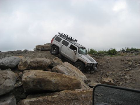 1991 Ford Bronco - Silver Hummer H3 navigates a rocky obstacle course during an off-road event.