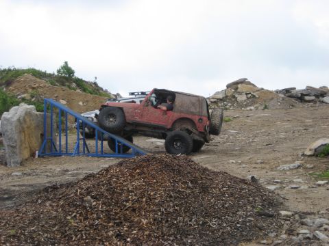 1991 Ford Bronco - A red Jeep Wrangler navigates an obstacle during an off-road event.