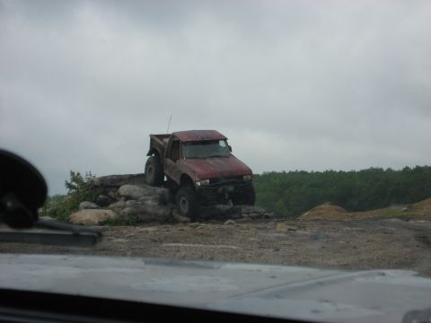 1991 Ford Bronco - A red pickup truck navigates a rocky obstacle course.