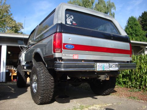 1989 Ford Bronco - This lifted 1989 Ford Bronco features a two-tone paint scheme with a red stripe and large off-road tires.