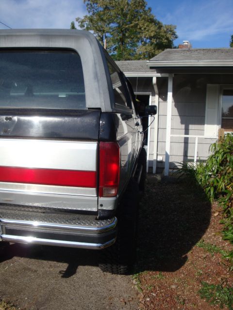 1989 Ford Bronco - This 1989 Ford Bronco features a two-tone paint scheme with a prominent red stripe and a gleaming chrome bumper.