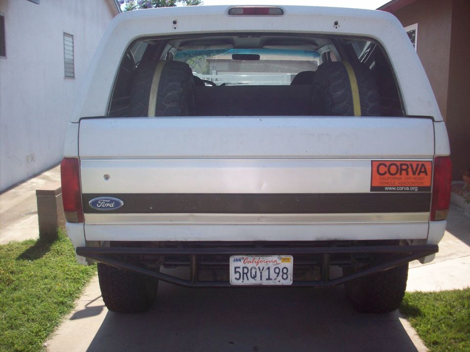 Rear view of a white Ford Bronco with two spare tires inside. Has a CORVA sticker on the right