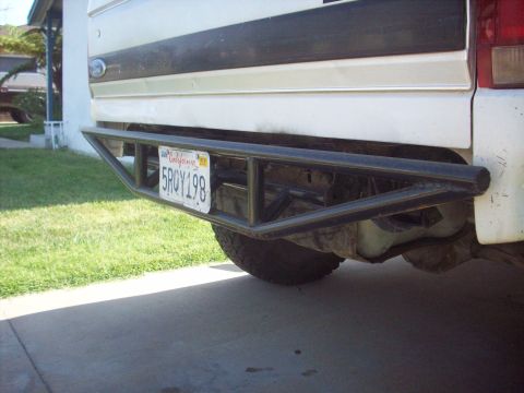 1995 Ford Bronco - The rear of a white Ford Bronco shows a custom metal bumper and a California license plate.