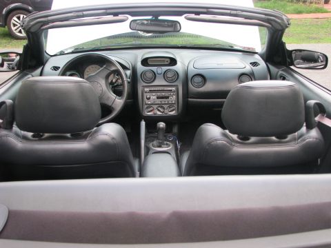 2001 Mitsubishi Eclipse - The interior of a convertible shows black leather seats and the dashboard with the radio and climate controls.