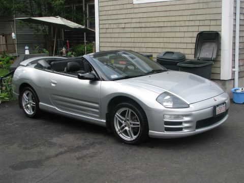 2001 Mitsubishi Eclipse - A silver convertible sports car is parked in front of a house with trash cans nearby.