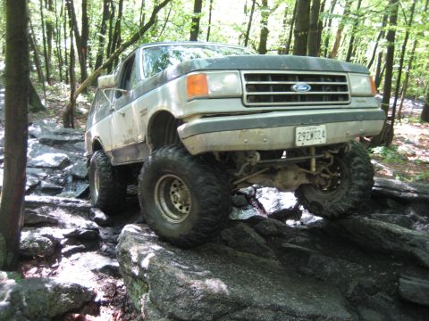 1991 Ford Bronco - This Ford Bronco is navigating a rocky trail in a wooded area.