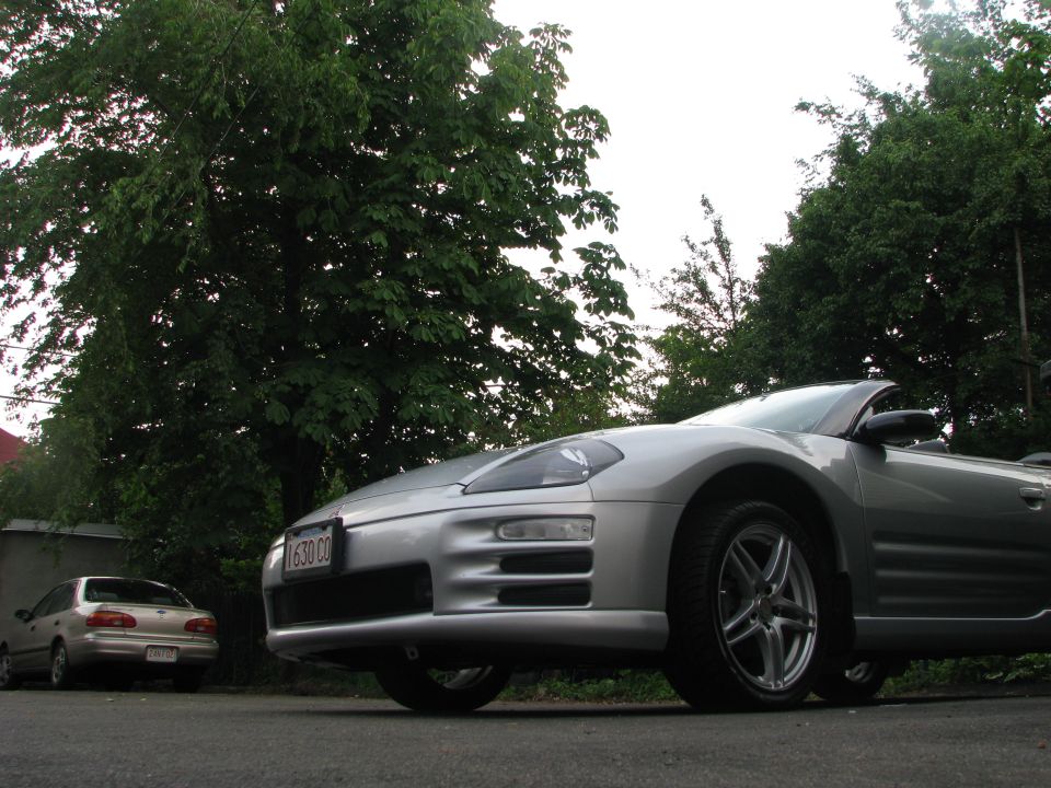 Silver convertible sports car, front quarter view, with a second car in the background