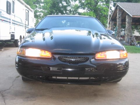 1996 Ford Thunderbird - The front of a black coupe is shown with its headlights illuminated.