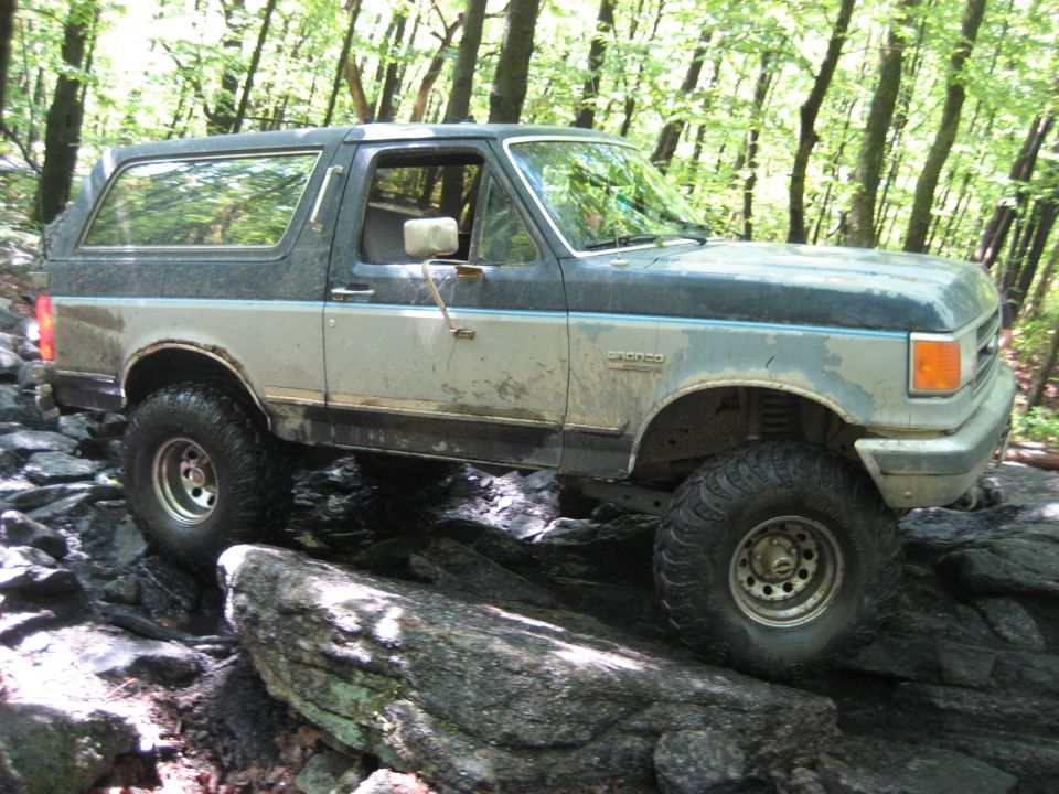 1991 Ford Bronco climbing over rocks on a trail