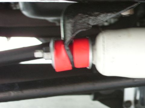 1978 Ford Bronco - Close-up view of red suspension bushings and a white shock absorber, likely part of a vehicle's undercarriage.