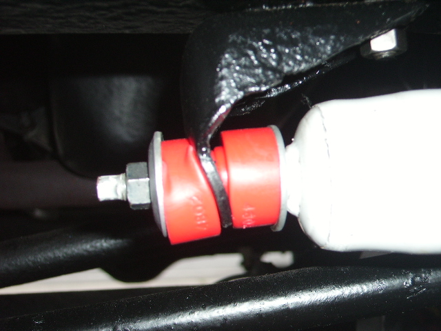 Close-up of red suspension bushings on a white shock absorber, with black metal components visible