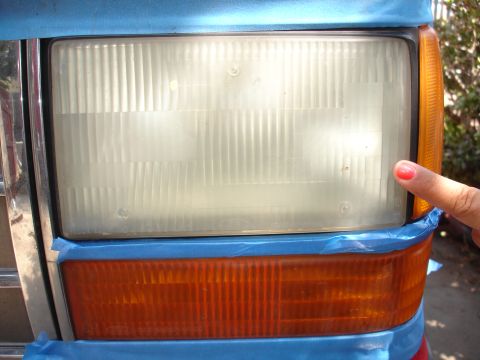 1992 Ford Explorer - A finger points to a taped-off headlight assembly, ready for restoration work.