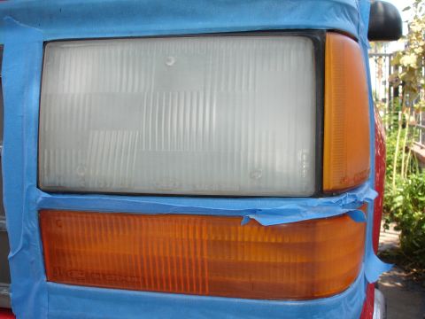 1992 Ford Explorer - Close-up of a vehicle's headlight and turn signal assembly being prepped for painting.