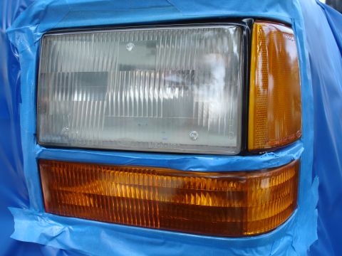 1992 Ford Explorer - Headlight and amber turn signal assembly on a 1992 Ford Explorer, prepared for detailing or repair with blue masking tape.