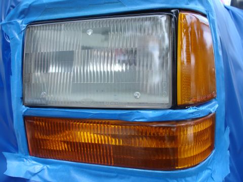 1992 Ford Explorer - Headlight assembly of a 1992 Ford Explorer, prepped for painting with blue masking tape.