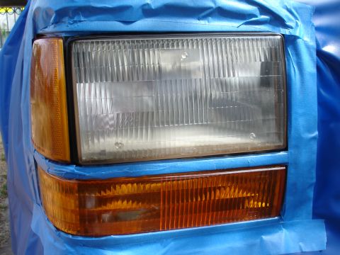 1992 Ford Explorer - Close-up of a 1992 Ford Explorer headlight assembly, masked for painting.