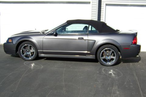 1993 Ford Bronco - Side view of a gray Ford Mustang convertible with the top up.