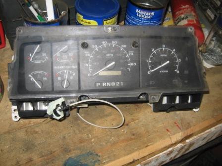 1993 Ford Bronco - A Ford truck instrument cluster removed from the dash and sitting on a workbench, showing the 85 mph speedometer with PRNDL indicator, tach…