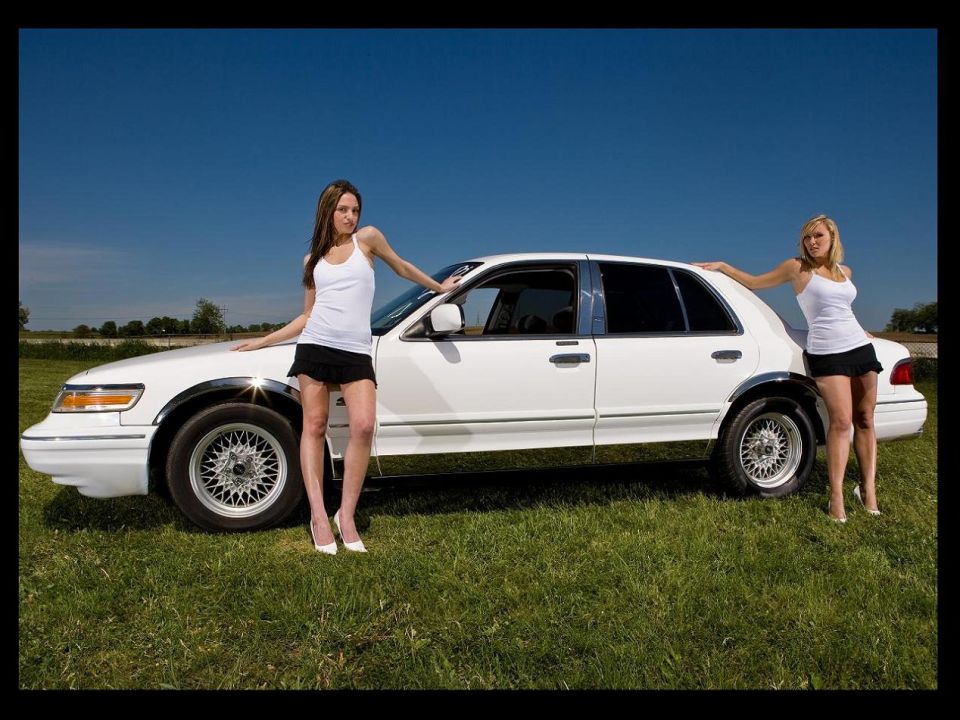 White 1997 Mercury Grand Marquis with two women posing on grass