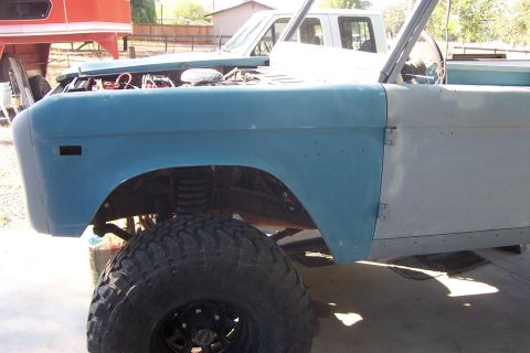 1976 Ford Bronco - A 1976 Ford Bronco is undergoing restoration, showing its body panels in various stages of paint preparation.