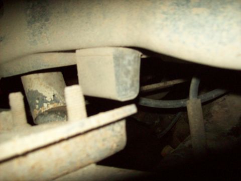 1985 Ford Bronco - A close-up view of underbody components, including a rubber mount and rusted metal parts.