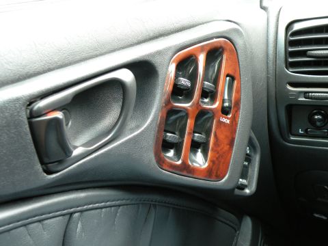 1998 Subaru Legacy - Close-up of a car's interior door panel showing power window controls and wood trim accents.