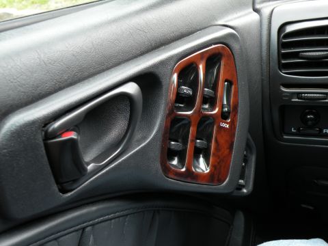 1998 Subaru Legacy - The interior door panel features wood grain trim around the power window and lock controls.